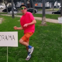 a man in a pink shirt is running with a sign that says  drama 